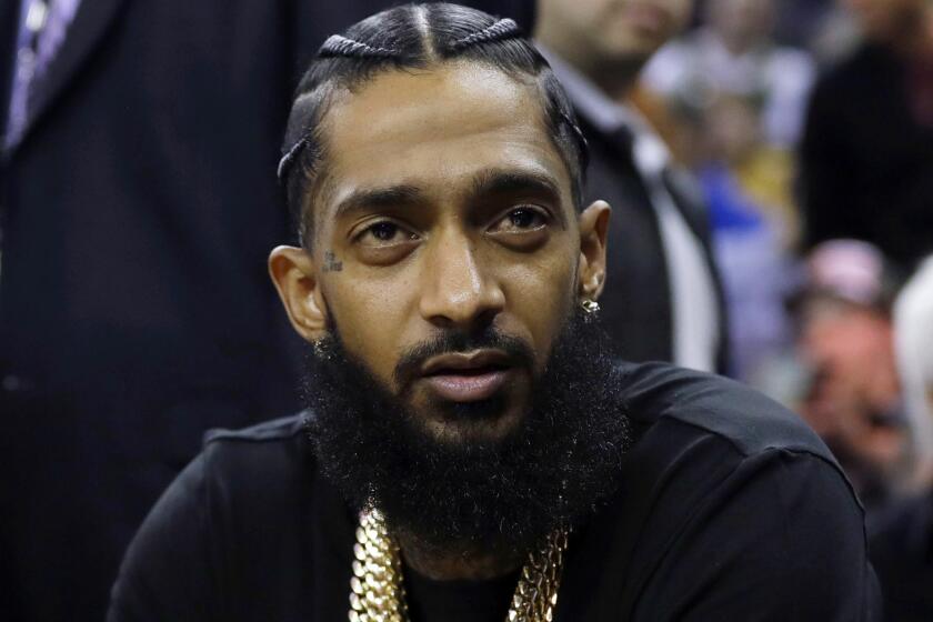 FILE - This March 29, 2018 file photo shows rapper Nipsey Hussle at an NBA basketball game between the Golden State Warriors and the Milwaukee Bucks in Oakland, Calif. Hussle was shot and killed Sunday, March 31, 2019 outside of his clothing store in Los Angeles. (AP Photo/Marcio Jose Sanchez, File)