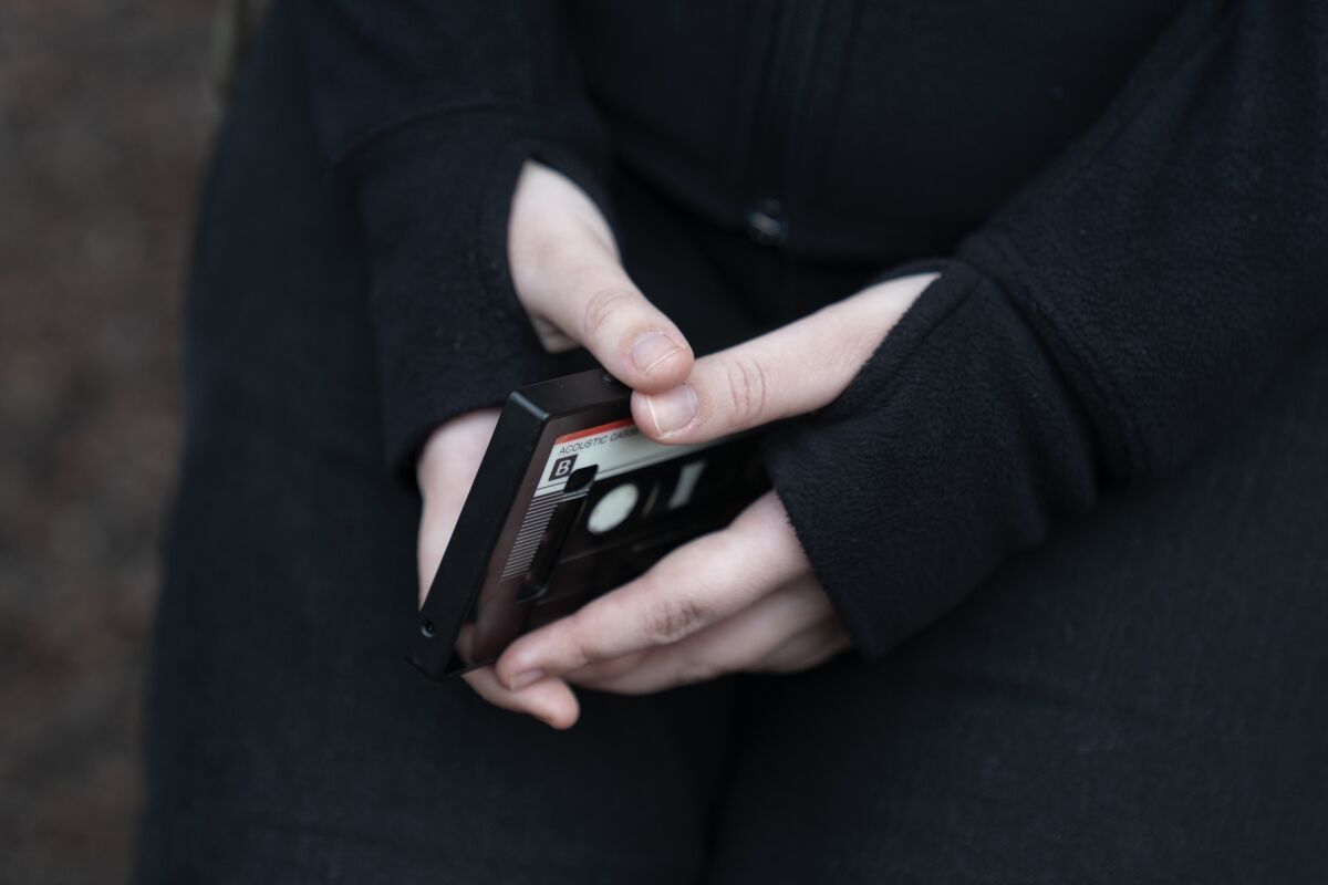 Archivo - Una adolescente sostiene su teléfono mientras se sienta para un retrato 