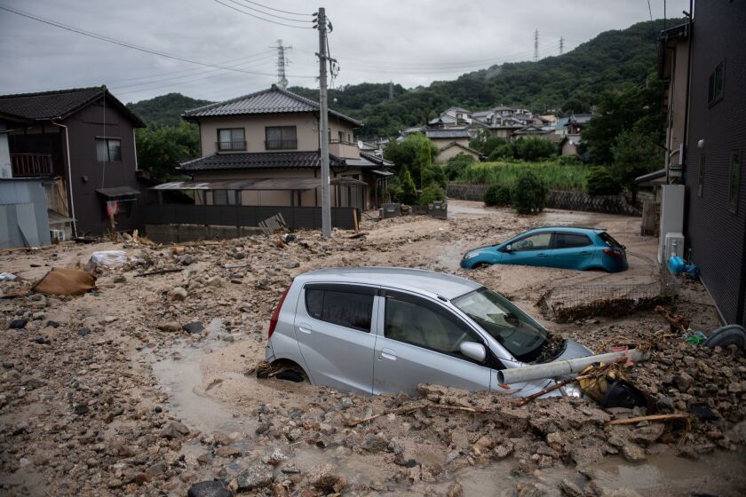 Cars trapped in the mud after floodwaters hit Saka, Hiroshima prefecture, on Sunday.