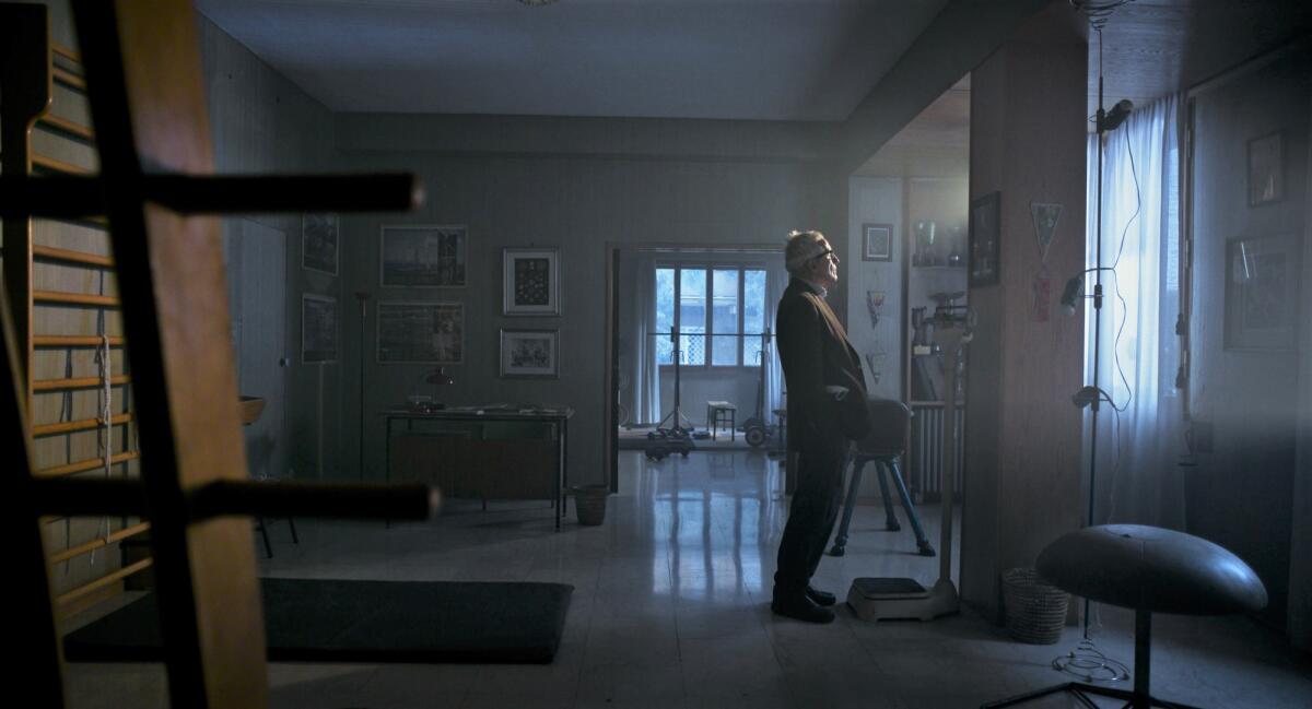 A man stands in a room, looking toward a window in “Marx Can Wait.”