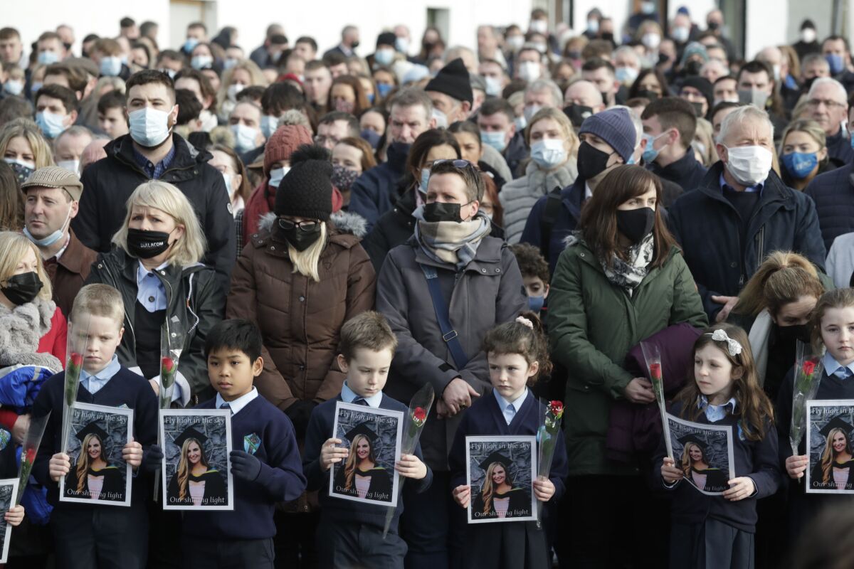 School children that were taught by Ashling Murphy holds pictures of their teacher outside St Brigid's Church, Mountbolus, Co Offaly, Ireland, at the end of the funeral, Tuesday, Jan. 18, 2022. Hundreds of mourners in Ireland turned out Tuesday for the funeral mass of a 23-year-old schoolteacher whose murder has reignited debate about how to tackle violence against women. The body of Ashling Murphy, a musician and teacher, was found on the banks of a canal in Tullamore in central Ireland on Jan.12. (Niall Carson/PA via AP)