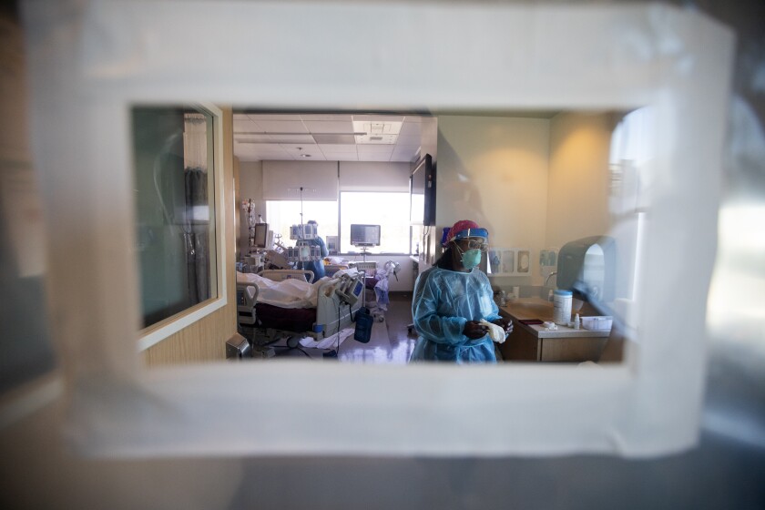 A nurse inside a negative pressure room is seen through a rectangular plastic window