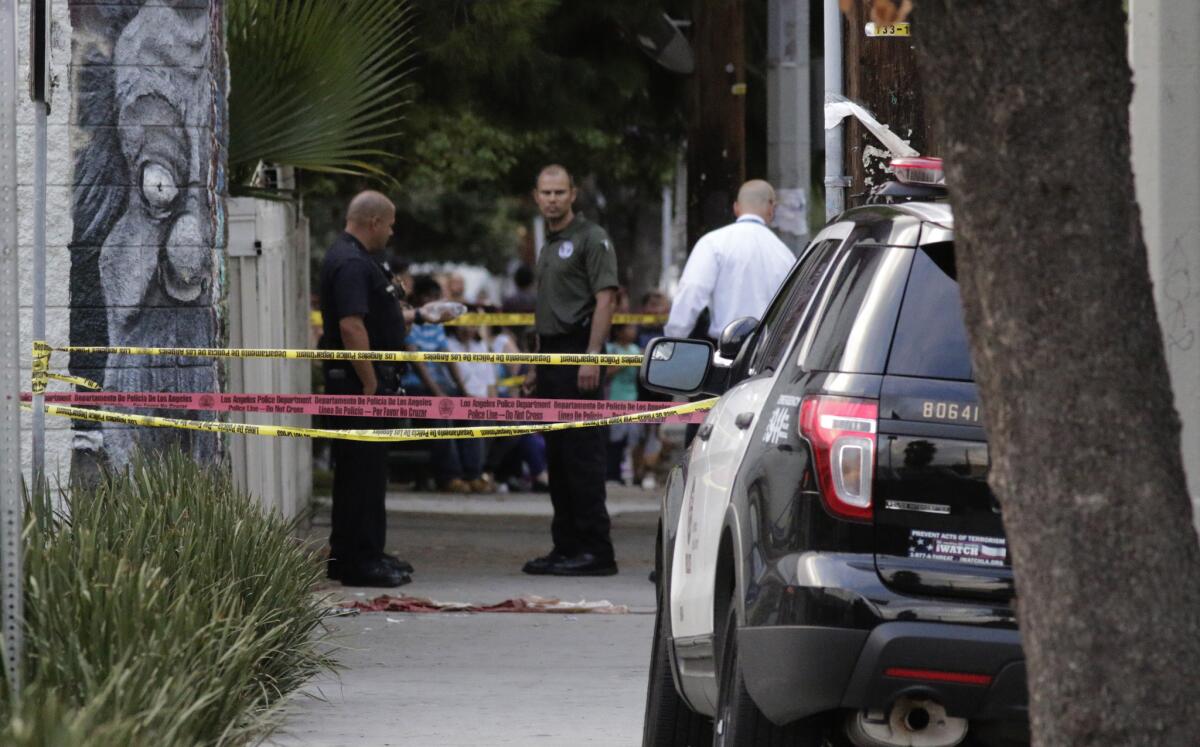 Investigators examine the scene where police fatally shot a man holding a gun Tuesday afternoon in the 14700 block of Parthenia Street in Panorama City.