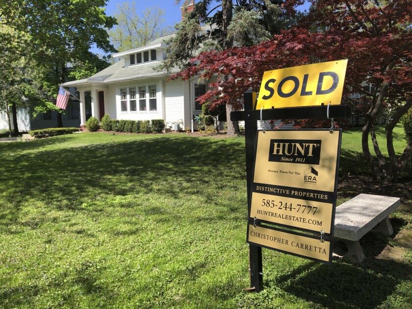 A sold sign on a lawn in front of a house.