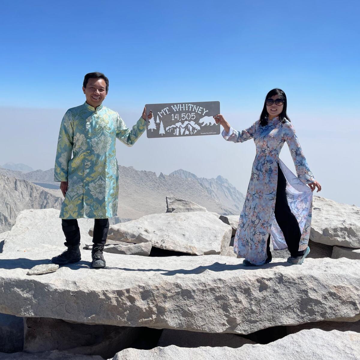  A man and woman, in traditional Vietnamese dress, hold a sign on Mt. Whitney.