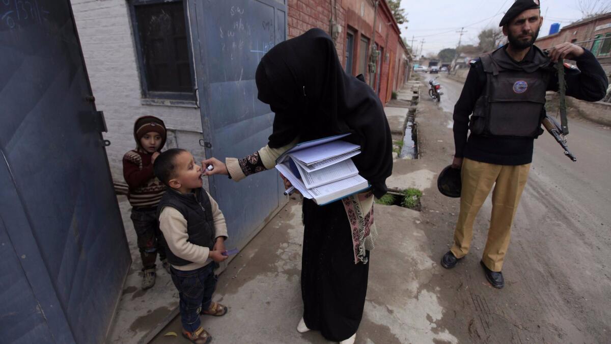 A police officer escorts a polio vaccination team during a three-day countrywide campaign in Peshawar, Pakistan. Attacks by Islamist militants against health workers and police guarding them remained a challenge for a U.N.-funded vaccination campaign.