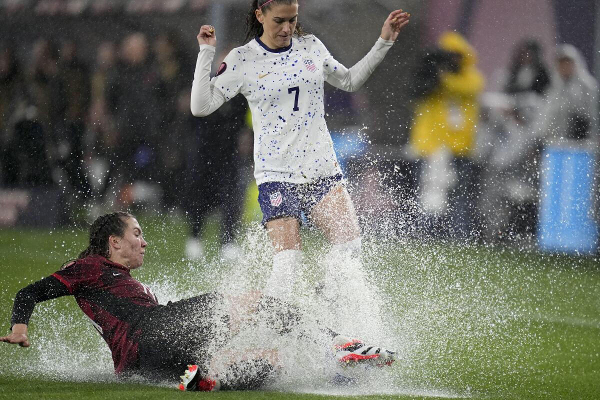 U.S. forward Alex Morgan collides with Canada's Vanessa Gilles and a puddle of water on the pitch