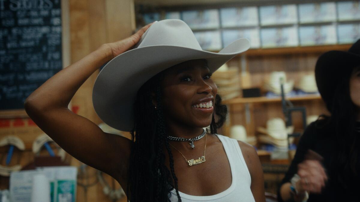 A woman in a cowboy hat smiles.