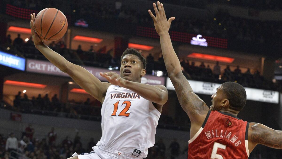 Virginia guard De'Andre Hunter (12) attempts a shot over the reach of Louisville center Malik Williams (5) during the first half of an NCAA college basketball game in Louisville, Ky., Saturday, Feb. 23, 2019. (AP Photo/Timothy D. Easley)