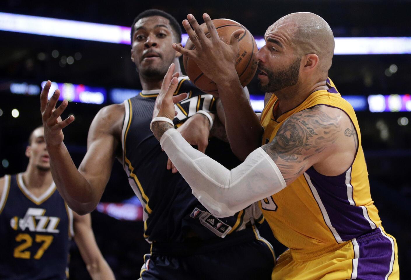 Lakers forward Carlos Boozer and Jazz center Derrick Favors get tangled battling for a rebound in the second half.