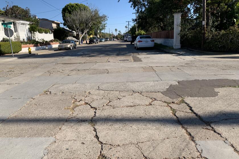 The intersection of La Canada and La Jolla Hermosa Avenue shows cracks and asphalt patches.