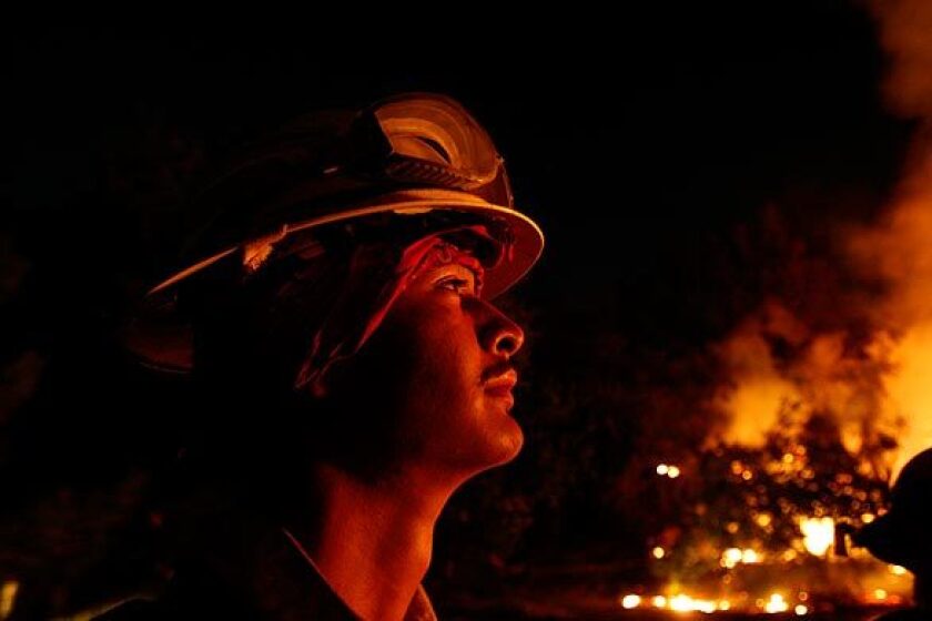 Matthew Cleaver, 20, of Arizona keeps an eye on a backfire near the corner of Rosemont Avenue and Rockdell Street in La Cresenta. The Forest Service set the backfire to help protect homes on the ridge.