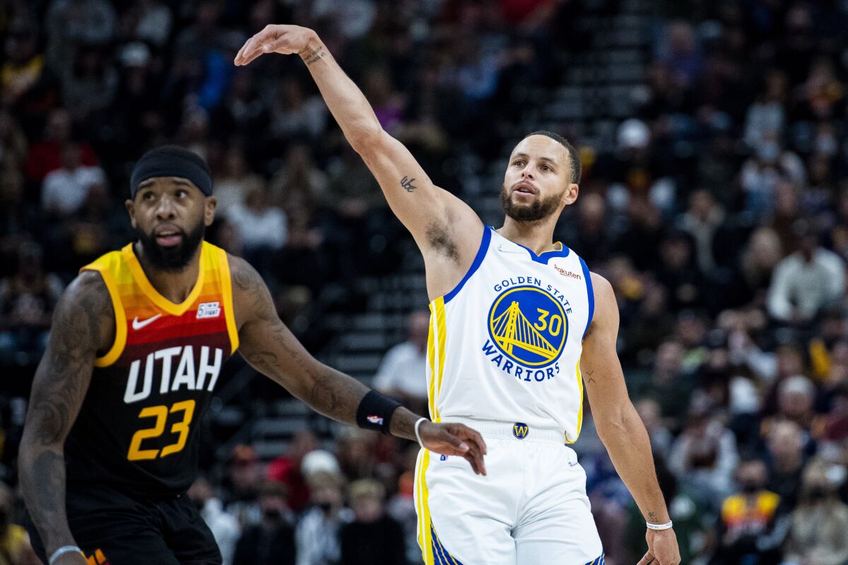 Golden State Warriors guard Stephen Curry (30) holds his follow-through on his shot while guarded by Utah Jazz forward Royce O'Neale (23) in the first half during an NBA basketball game Saturday, Jan. 1, 2022, in Salt Lake City. (AP Photo/Isaac Hale)