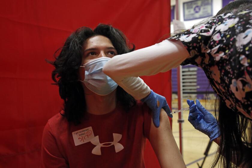 LOS ANGELES, CA - MAY 17: Aragon Leep, 17, is vaccinated with Pfizer at the Manual Arts High School basketball and gym building in downtown on Monday, May 17, 2021 in Los Angeles, CA. The school is one of 200 sites that the Los Angeles Unified School District has deployed mobile vaccination teams to get as many shots into students' arms as possible. (Dania Maxwell / Los Angeles Times)