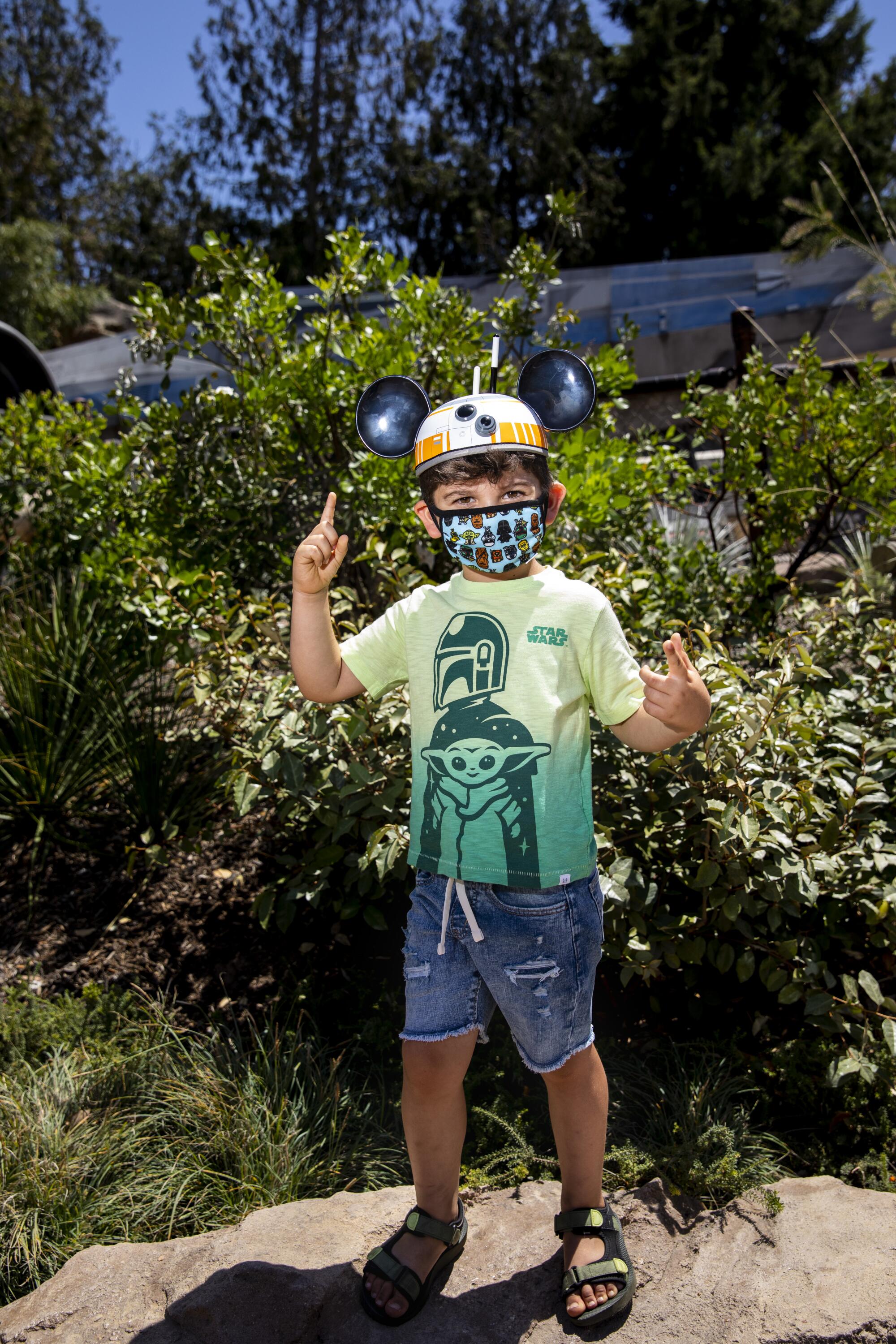 A boy wears a "Mandalorian" T-shirt and BB-8 ears.