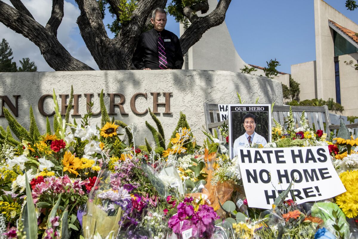 A man looks over a sidewalk memorial with flowers and a photo