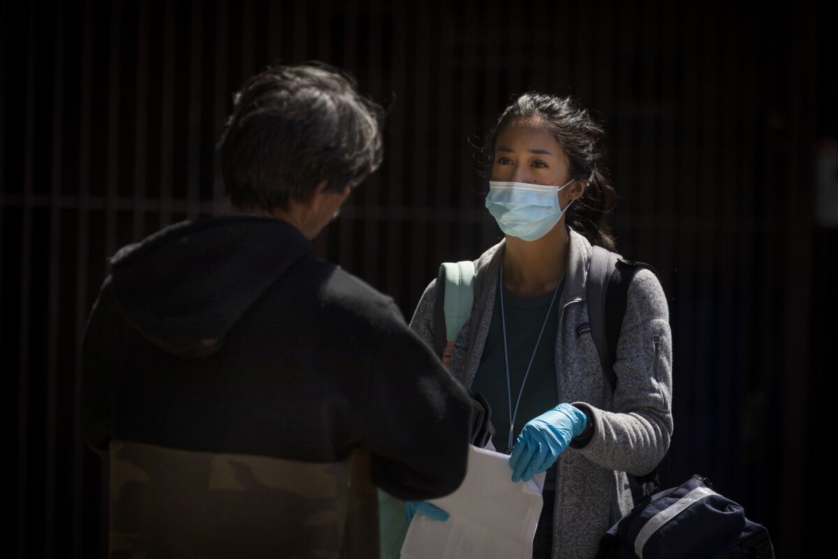 Nurse practitioner Jen King, right, speaks with a man living in an encampment on a Los Angeles sidewalk. "I feel like when you sign up for this job, you sign up to take certain risks and you have to treat people as safely as you can," she said.