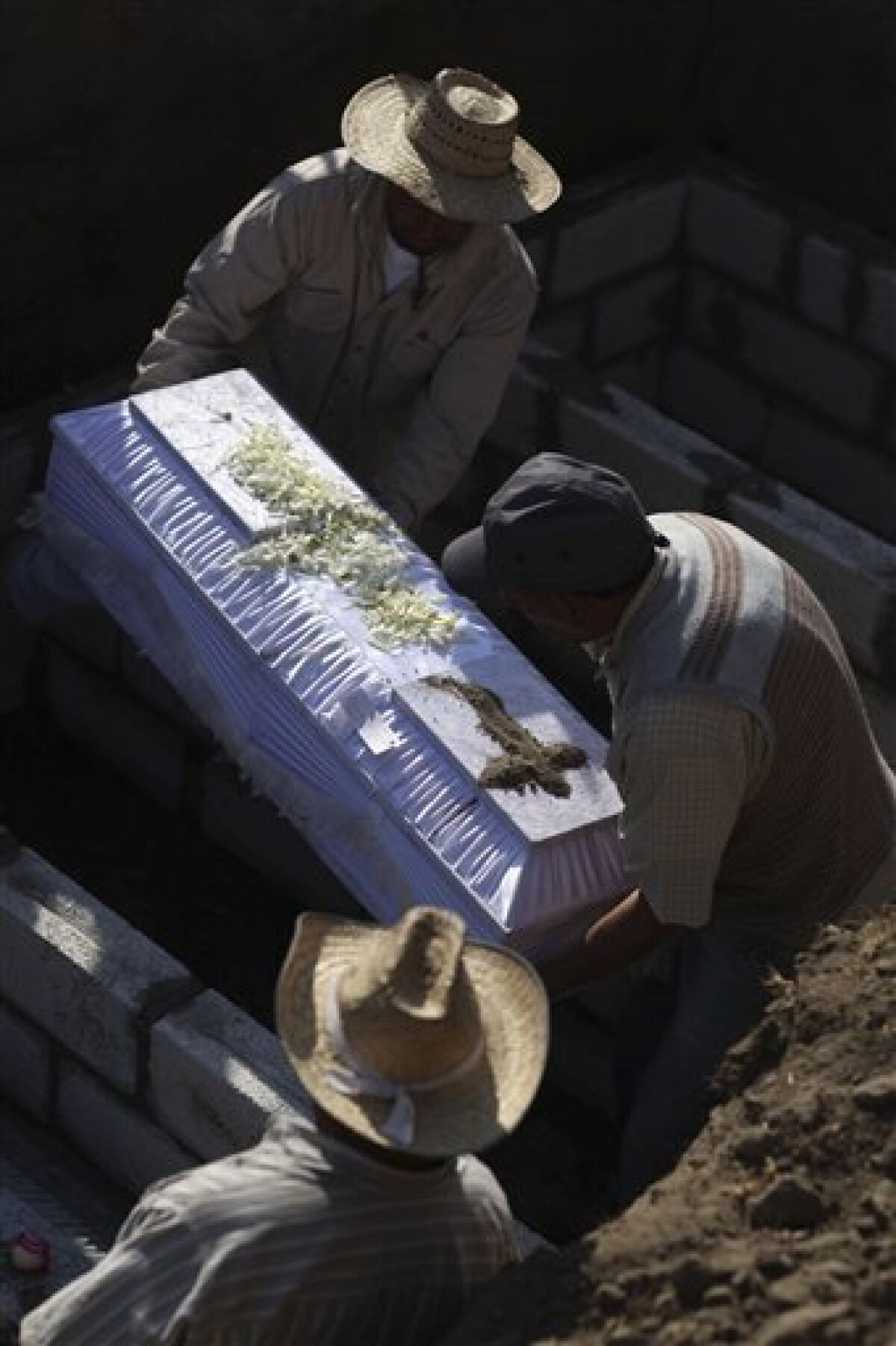 People bury a victim of the oil pipeline explosion in a cemetery in San Geronimo, Mexico, Monday Dec. 20, 2010. The Sunday explosion in the nearby town of San Martin Texmelucan laid waste to parts of the central Mexican city, incinerating people, cars, houses and trees as gushing crude turned streets into flaming rivers. At least 28 people were killed, 13 of them children, in a disaster authorities blame on oil thieves. (AP Photo/Alexandre Meneghini)