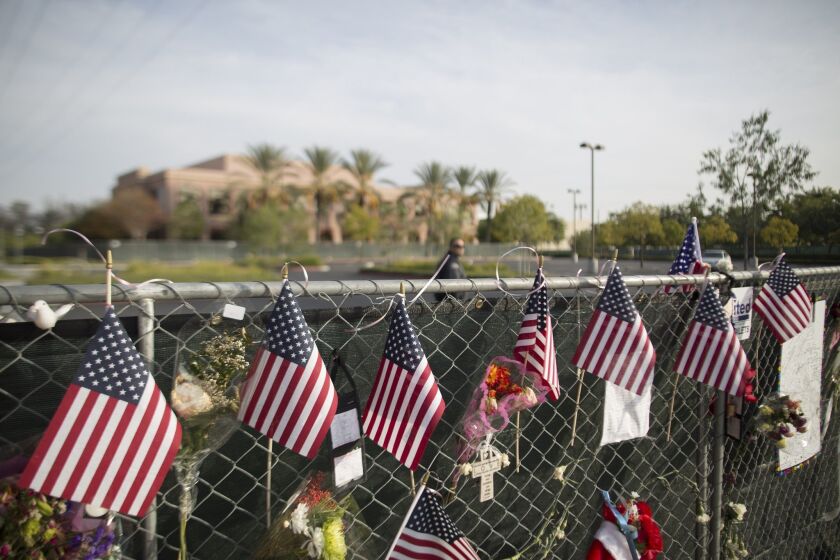 A security guard patrols the empty parking lot of the Inland Regional Center in San Bernardino, the site of a Dec. 2 massacre by Syed Farook and Tashfeen Malik. The perimeter fence of the center is covered with memorial items on Dec. 21.
