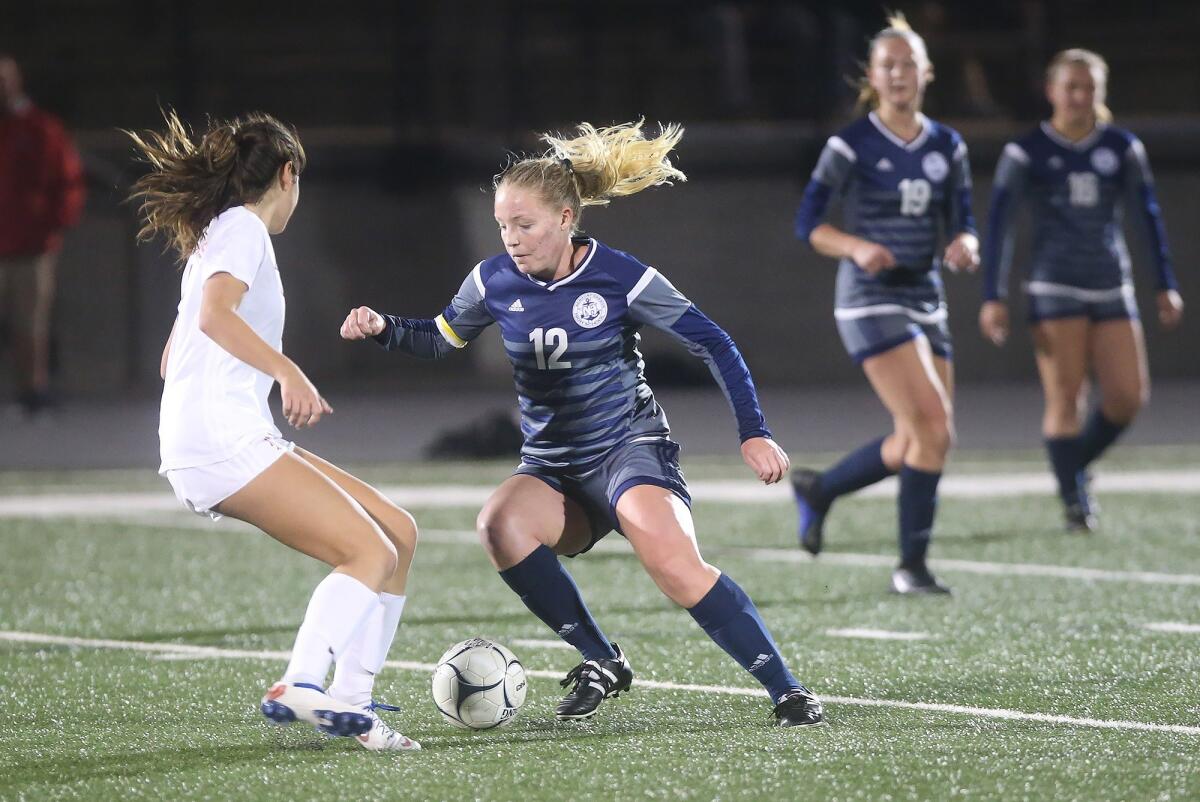 Newport Harbor's Emily Johnson (12) dribbles past a Los Alamitos defender in the quarterfinals of the CIF Southern Section Division 1 playoffs at Davidson Field on Feb. 12.