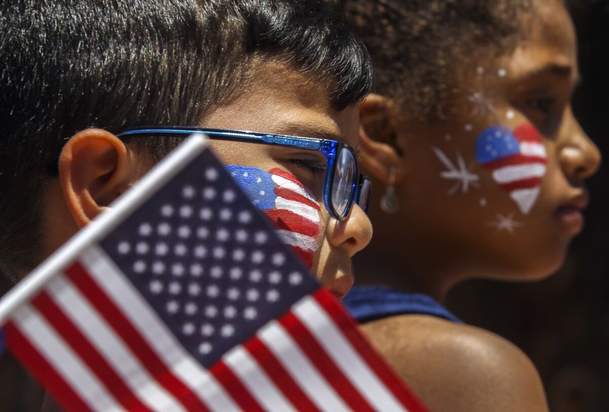Children with face painting of American flags participate in a July Fourth parade.