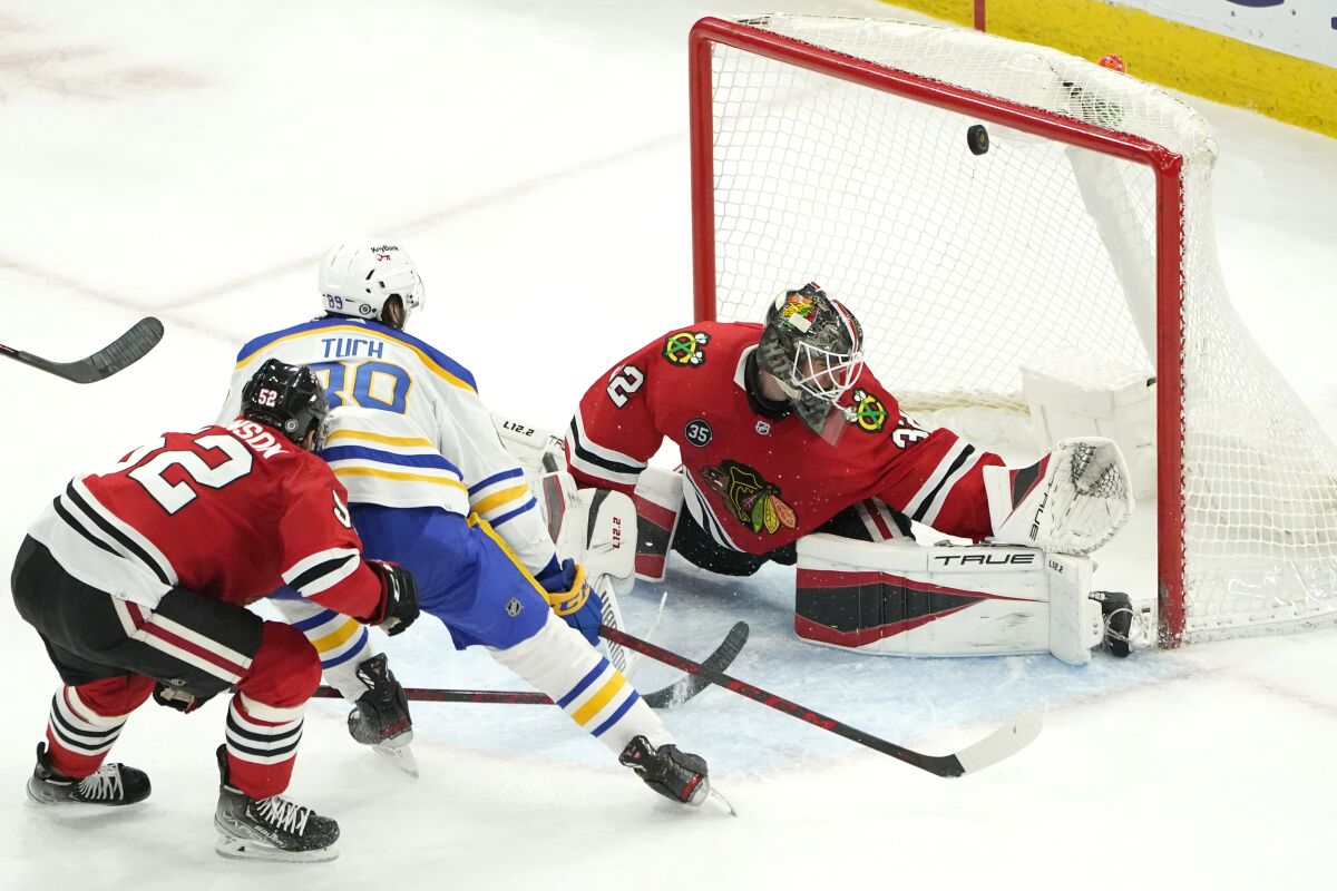 Buffalo Sabres' Alex Tuch (89) watches his shot score past Chicago Blackhawks goaltender Kevin Lankinen as Reese Johnson also defends during the third period of an NHL hockey game Monday, March 28, 2022, in Chicago. The Sabres won 6-5. (AP Photo/Charles Rex Arbogast)
