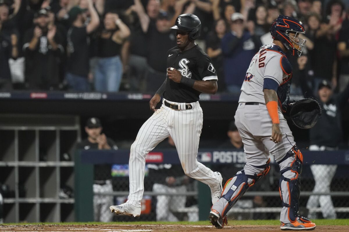 Chicago White Sox's Tim Anderson, left, scores on a Eloy Jimenez single as Houston Astros catcher Martin Maldonado waits for the throw in the first inning during Game 3 of a baseball American League Division Series Sunday, Oct. 10, 2021, in Chicago. (AP Photo/Nam Y. Huh)
