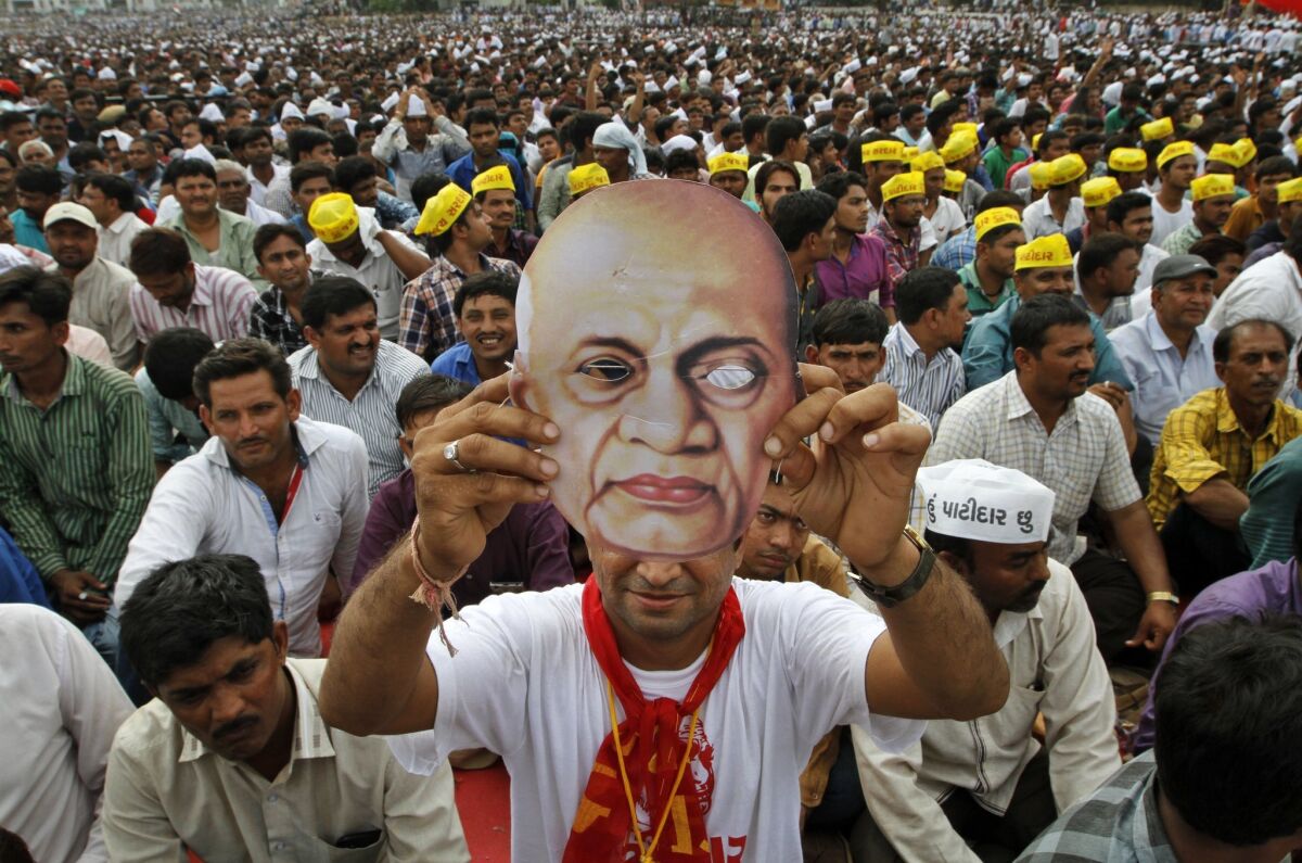 A Patidar, or member of Patel community, holds a mask of Indian freedom fighter and first Home Minister of Independent India Sardar Vallabhbhai Patel as he participates in a rally in Ahmadabad, India, Tuesday, Aug. 25, 2015.