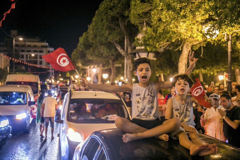 Children waving Tunisian flags in a crowd