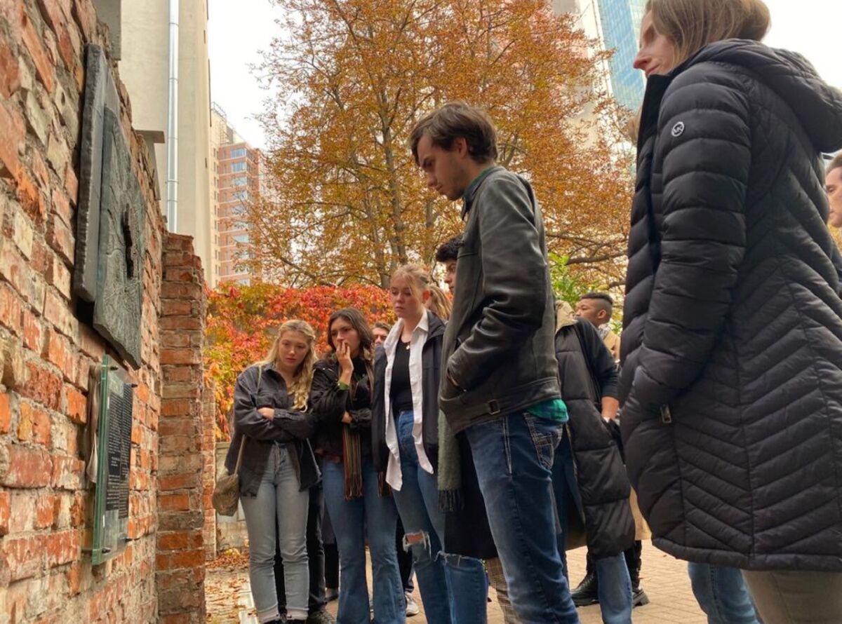 Students read plaques on an old wall in the Jewish ghetto in Lodz, Poland.