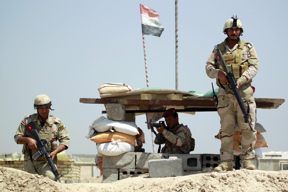 Iraqi government forces pose for a picture at a checkpoint in the Jurf al-Sakher area about 30 miles south of Baghdad.