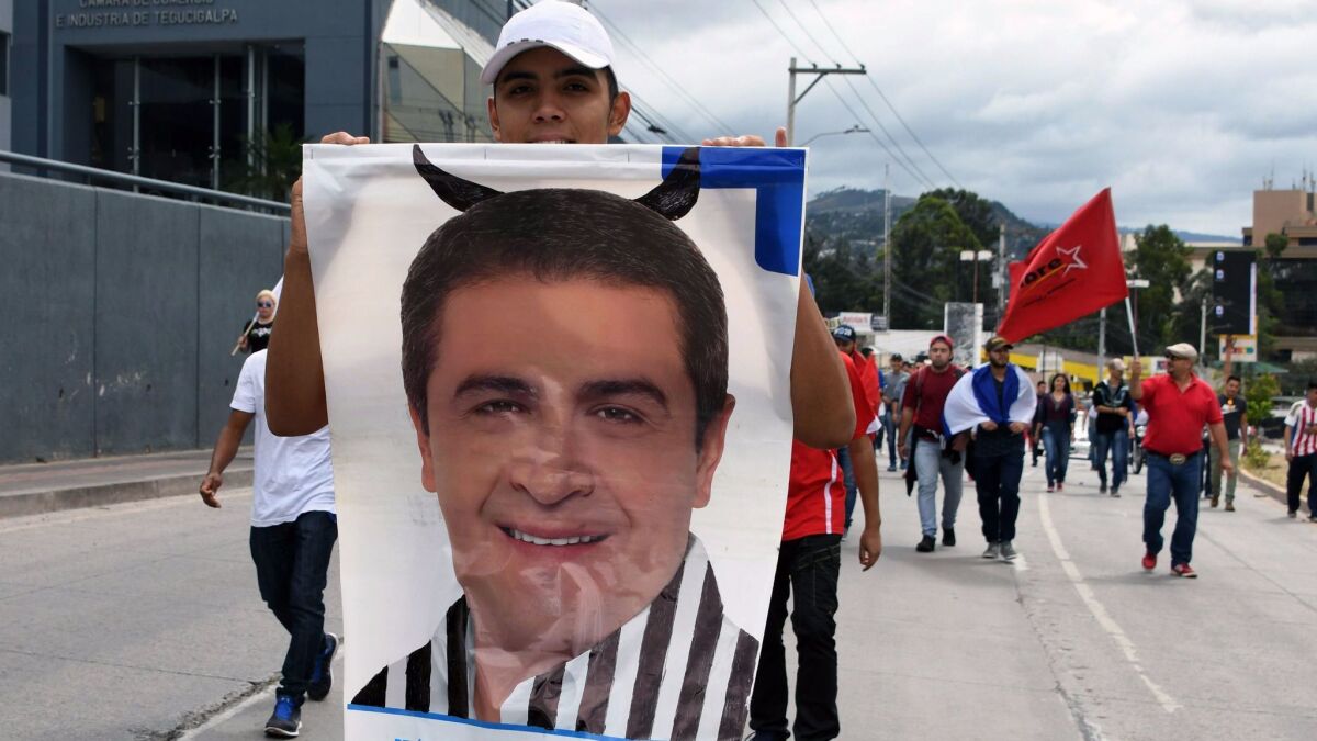 A supporter of opposition candidate Salvador Nasralla holds a poster of President Juan Orlando Hernandez during a march Sunday in Tegucigalpa, Honduras.