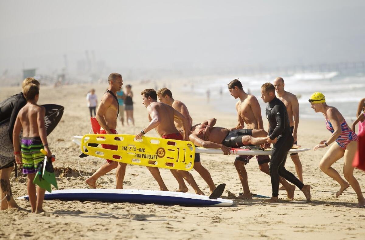 A swimmer is carried off the beach after being bitten by a shark near the Manhattan Beach Pier on Saturday.