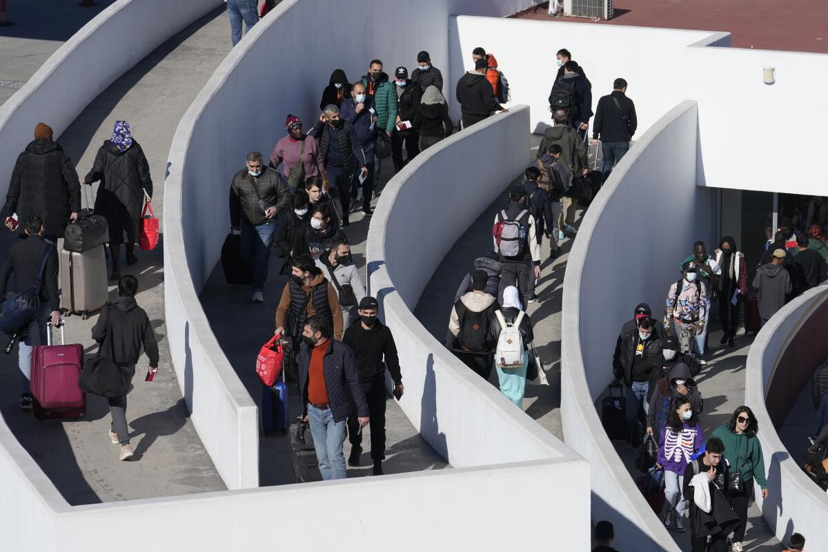 Migrants seeking asylum enter the U.S. on a walled walkway