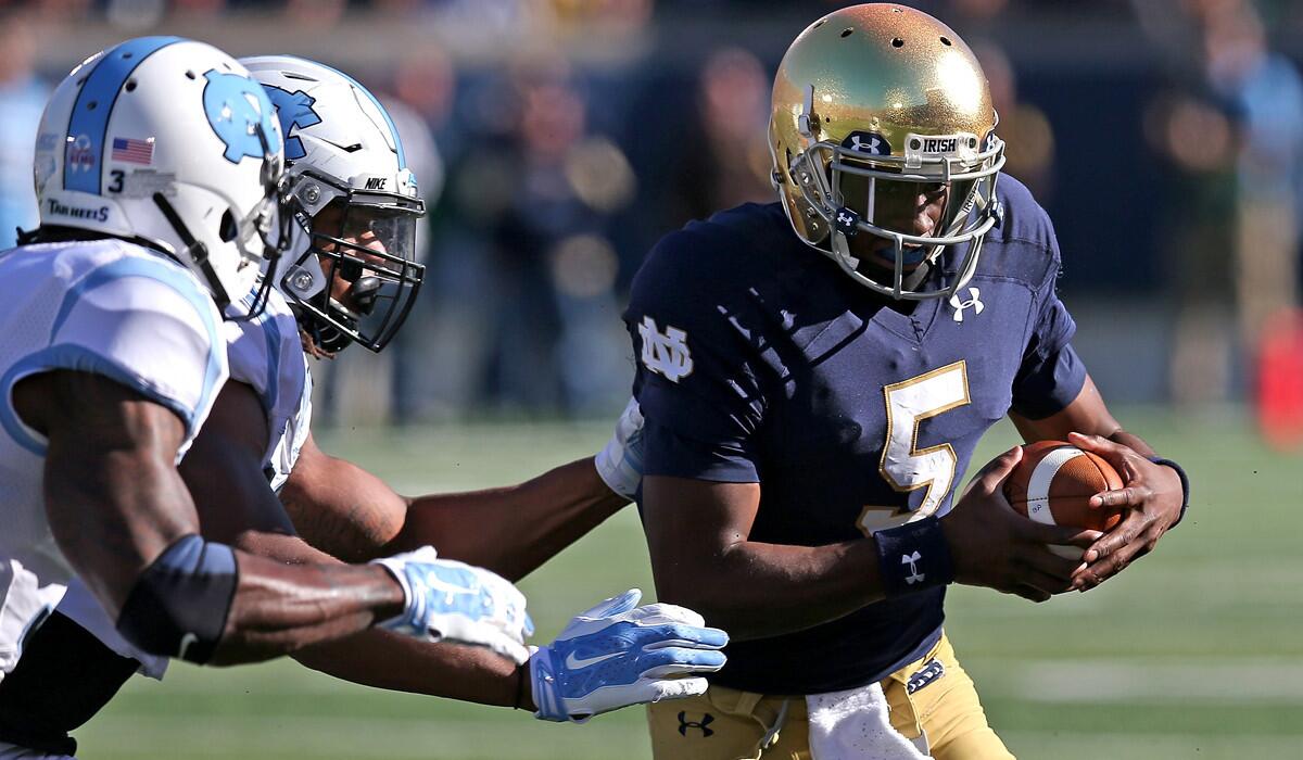 Notre Dame quarterback Everett Golson (5) scrambles against North Carolina defenders Sam Smiley, left, and Dajaun Drennon on Saturday afternoon.