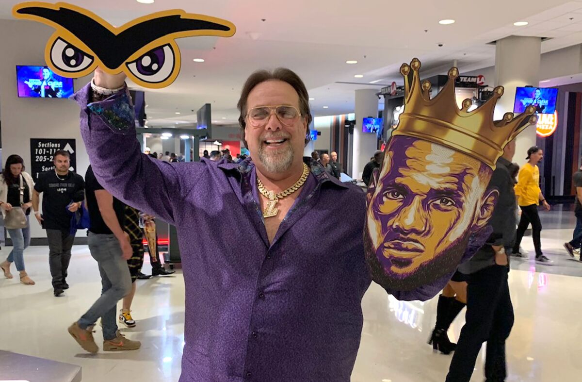 Gary Martin Zelman poses with two of his signs during the Lakers’ season-opening game against the Clippers at Staples Center on Tuesday.