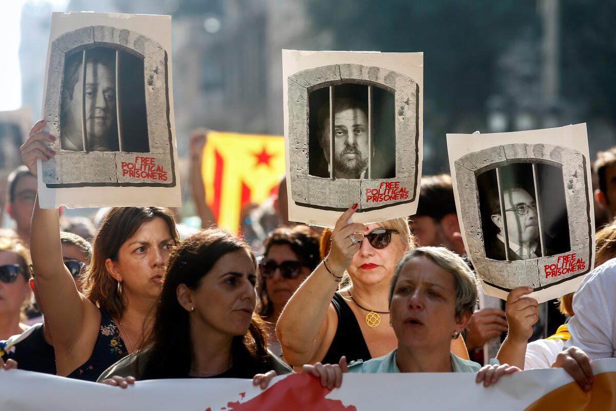 People hold portraits of some of the Catalan political leaders who were sentenced to prison after the Supreme Court delivered its sentence, in Barcelona.