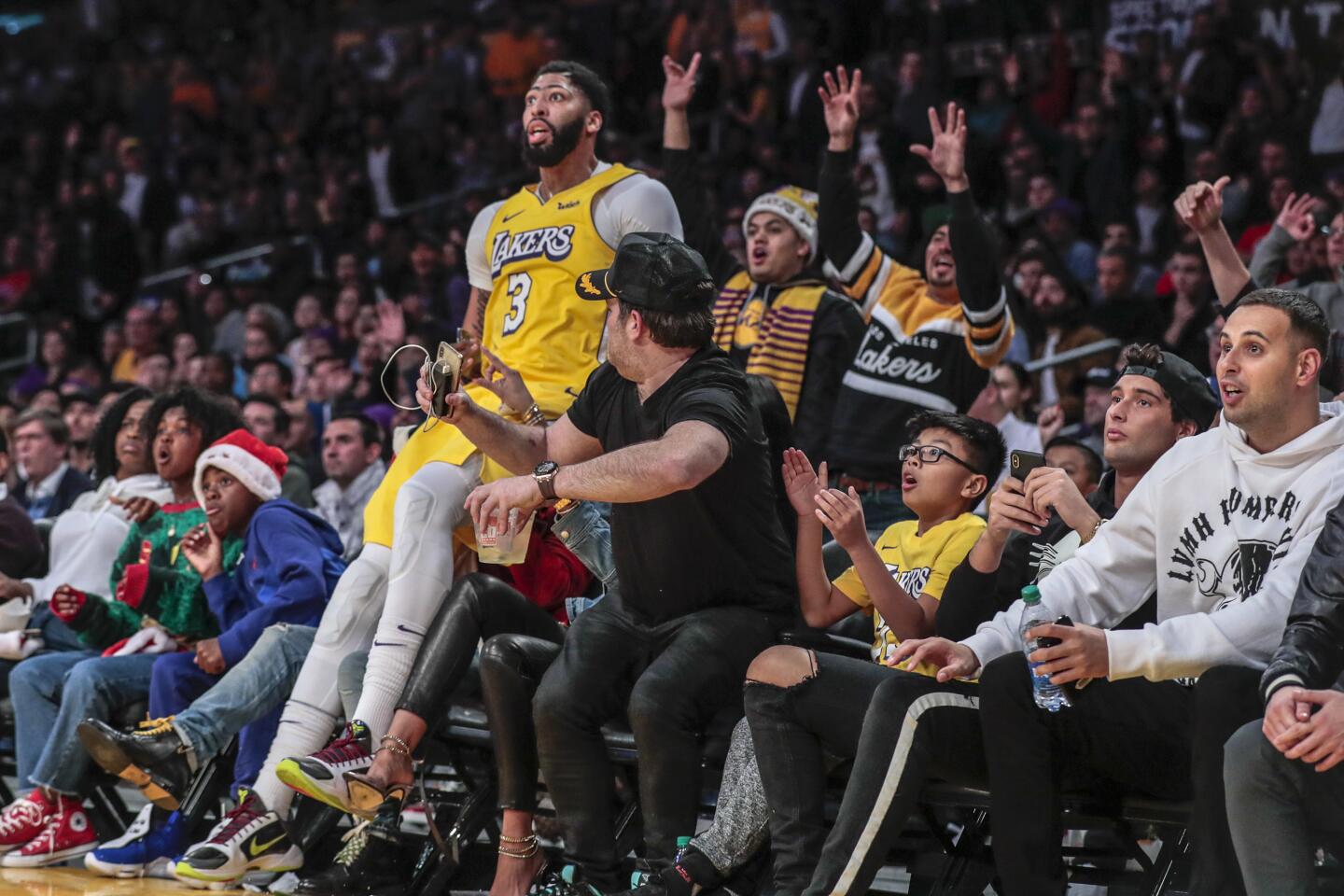 Lakers forward Anthony Davis falls into the courtside seats near comedian Kevin Hart (hidden from view) at the end of the first half.