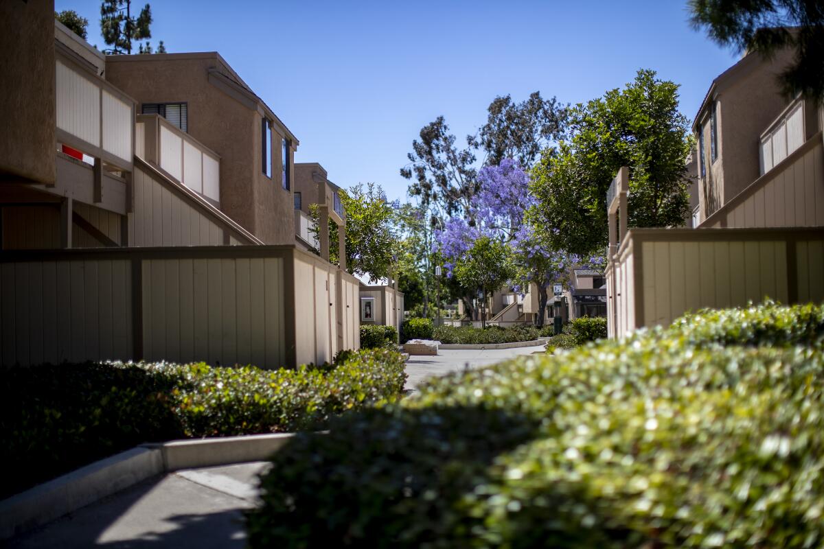 Apartment buildings face each other with a walkway and shrubs between them.