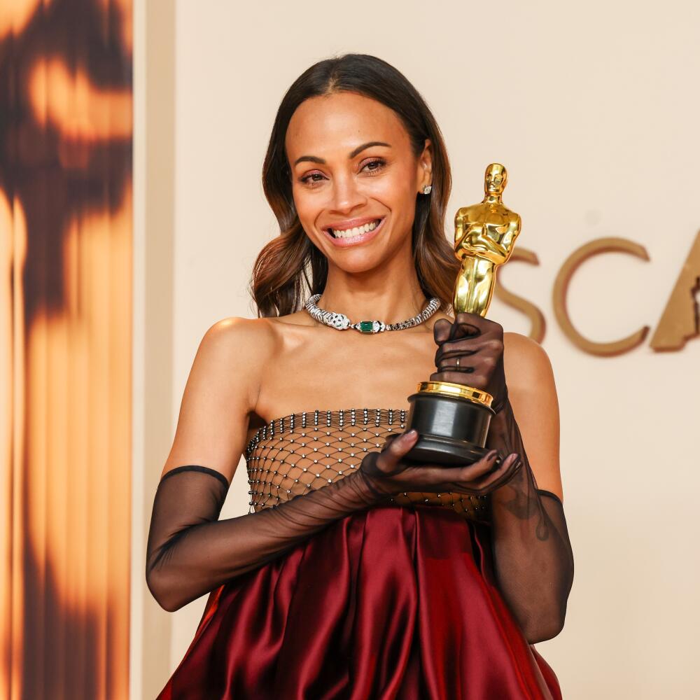 A woman with brown hair holds an Oscar.