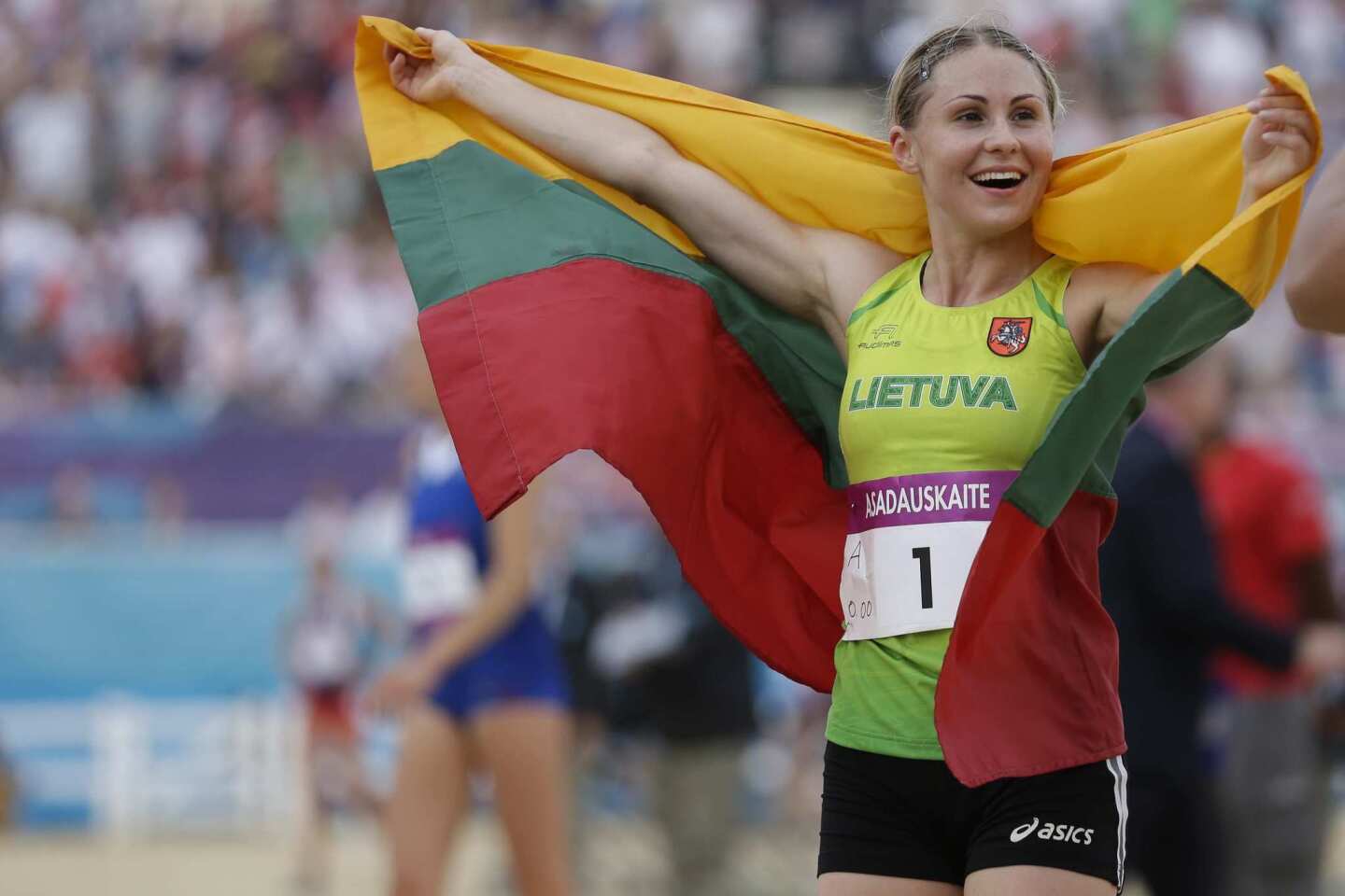 Laura Asadauskaite of Lithuania celebrates with her national flag after she won the gold medal in the women's modern pentathlon.