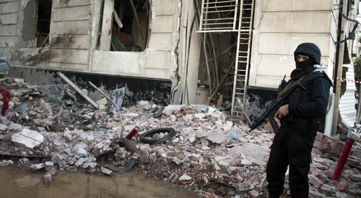 An Egyptian policeman guards the scene of an explosion at a police headquarters in the Nile Delta city of Mansoura. At least 15 people were killed.