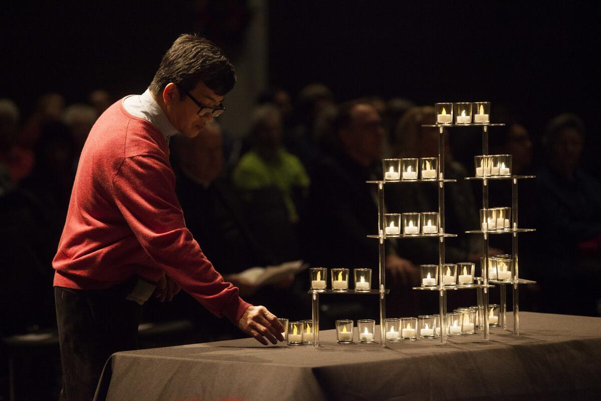 Father Loc Tran places a candle on a table as names of 210 men, women and children who died on the streets of Orange County are read aloud during the Homeless Persons' Inter-religious Memorial Service at Christ Cathedral in Garden Grove on Dec. 21.