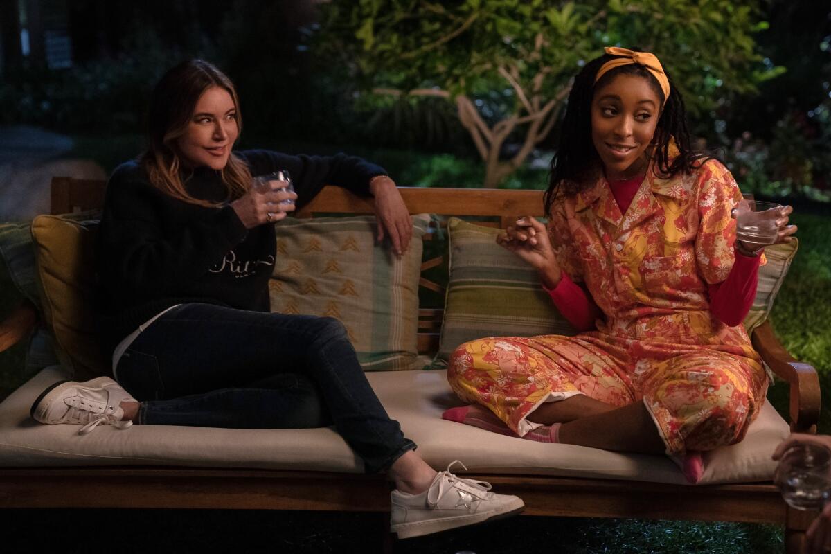 Christa Miller and Jessica Williams drink wine on an outdoor bench in a scene from "Shrinking."