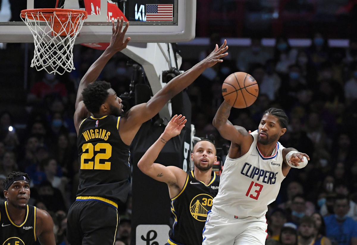 Clippers guard Paul George passes under pressure from Golden State's Andrew Wiggins and Stephen Curry.
