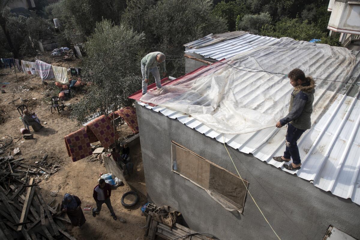 Palestinians cover the roof of their house with nylon to protect it from rain leaks after it was damaged during the 11-day Gaza war in May 2021, in the town of Beit Lahiya, northern Gaza Strip, Monday, Nov. 21, 2021. The first rainstorm of winter sent water pouring into homes across the Gaza Strip that were damaged during the 11-day war in May between Israel and the Palestinian territory's militant Hamas rulers. (AP Photo/Khalil Hamra)