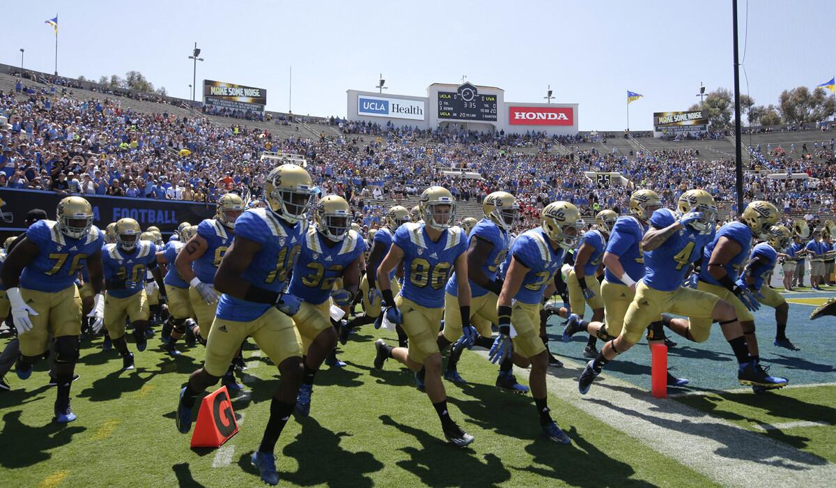 UCLA players run onto the field before a game at the Rose Bowl.