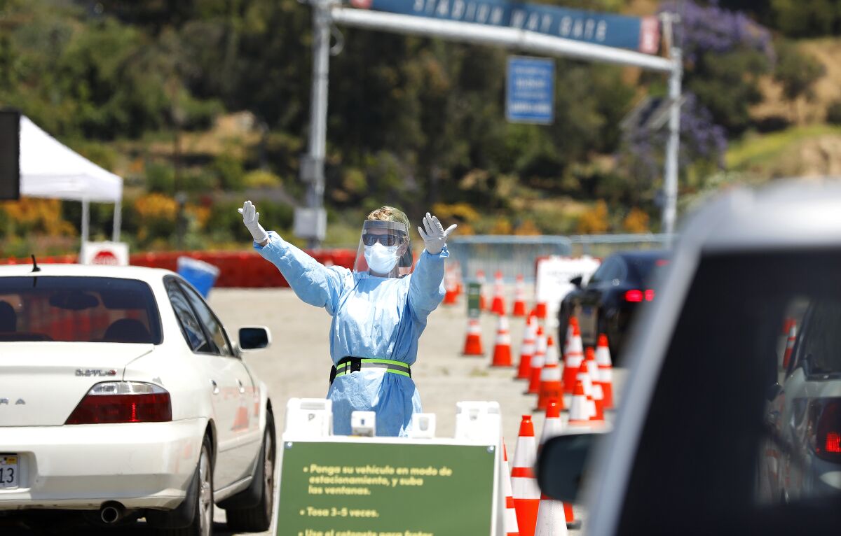 A person directs traffic at a drive-through coronavirus testing site at Dodger Stadium. 