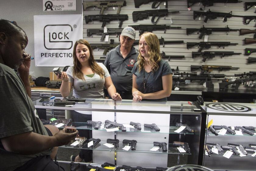 Store managers Jamie Taflinger, left, and Kendyll Murray show customer Cornell Hall, of Highland, different types of ammo at the Get Loaded gun store in Grand Terrace.