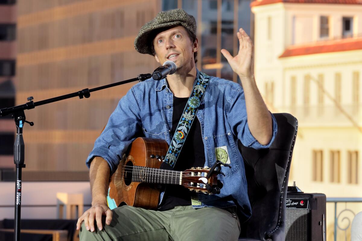 Jason Mraz with a guitar, speaking on stage